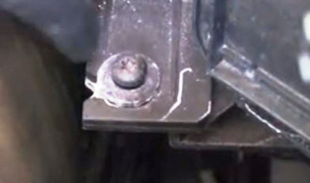 The third screw, at the rear, and lower down