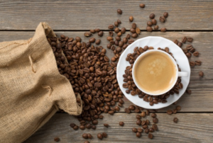 Cup of coffee next to a bag of spilled coffee beans.