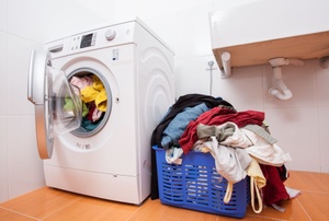 A washing machine next to a laundry basket.
