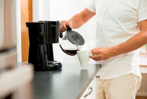 A man uses a coffeemaker.