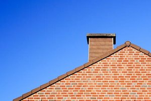 A home roof with a brick chimney extending above it.