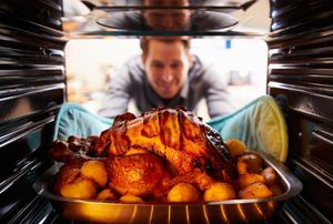 A man taking out a pan of food from an oven.