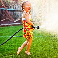 Little girl spraying water hose.