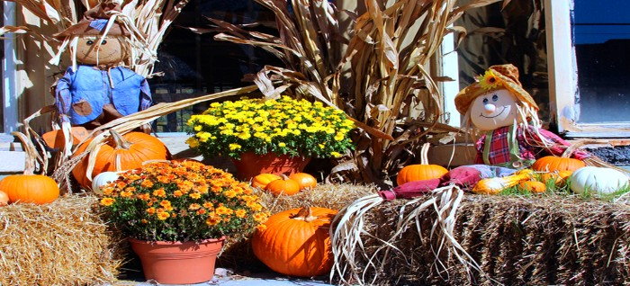 fall display with straw bales, pumpkins and scarecrow