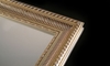 A close picture of a mirror with an elegant frame.
