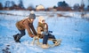 Two kids playing on a sled in the snow.