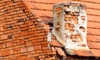 broken brick and mortar chimney on brick building with terracotta roof
