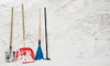 A set of snow removal tools, including a shovel and broom, against a snowy background. 