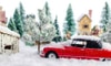 A winter scene of snow and small toys including a red car. 