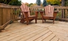 Two wooden Adirondack chairs on a backyard deck.