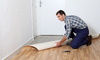 Linoleum flooring being rolled out by a person
