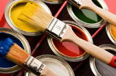 several paint cans in different colors with paint brushes on top