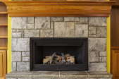 fireplace insert surrounded by a stone and wood mantle.