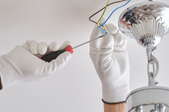 gloved hands attaching ceiling light fixture wires