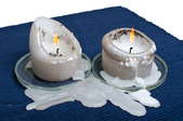 A pair of candles dripping wax on a table cloth.