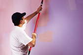 A man painting a room two shades of purple.