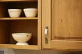a kitchen cabinet with dishes on a shelf next to it