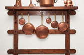 Copper utensils hanging on a rack.