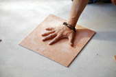 a hand pressing a tile down on the ground