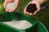 hands holding fertilizer and soil over fertilizer container and grass