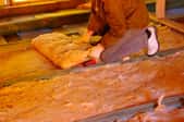 A worker adding batt insulation to a floor.