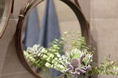 Leather mirror on the wall with flowers in front