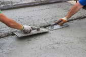 Trowels smoothing and leveling the surface of wet concrete.