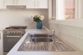 A stainless steel kitchen sink in a pristine kitchen.