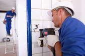 A professional drilling holes in ceramic tile for fixtures.