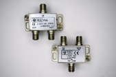 Two coax, or coaxial, splitters sit against a white surface.