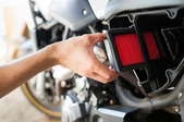 hand replacing air filter on motorcycle