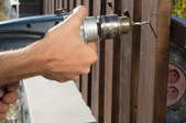 hands drilling metal panels onto fence