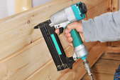 A nail gun being used to nail wood boards to supports.