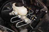 A brake master cylinder still attached under the hood of a Ford Mustang.