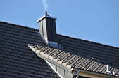smoke drifting out of a chimney on a roof