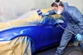 A man painting a car blue.
