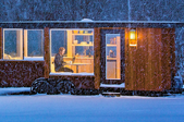 man working on computer in mobile home in a snowy forest