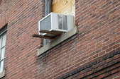 Side of a brick building with a window AC unit installed in a window