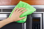 A stainless steel microwave and a cleaning rag.