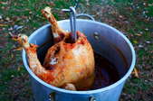 A turkey deep frying in a backyard.
