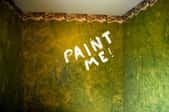An old wallpapered room with the words Paint Me on one wall