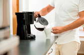 A man uses a coffeemaker.