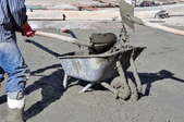 Two workers pouring concrete from a wheelbarrow.