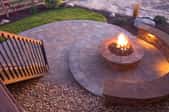 Circular fire pit at dusk on a flagstone patio.
