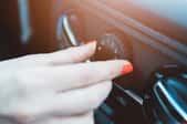 A female hand adjusting the vent on a car dashboard.