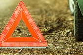 An emergency triangle next to a car tire.
