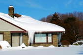 A house with snow-covered roof and ice hanging from gutters.