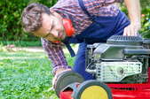 man checking broken lawn mower