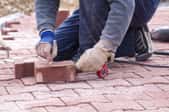 Person laying decorative bricks on a pathway