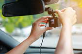 hands adjusting small camera and screen on car windshield